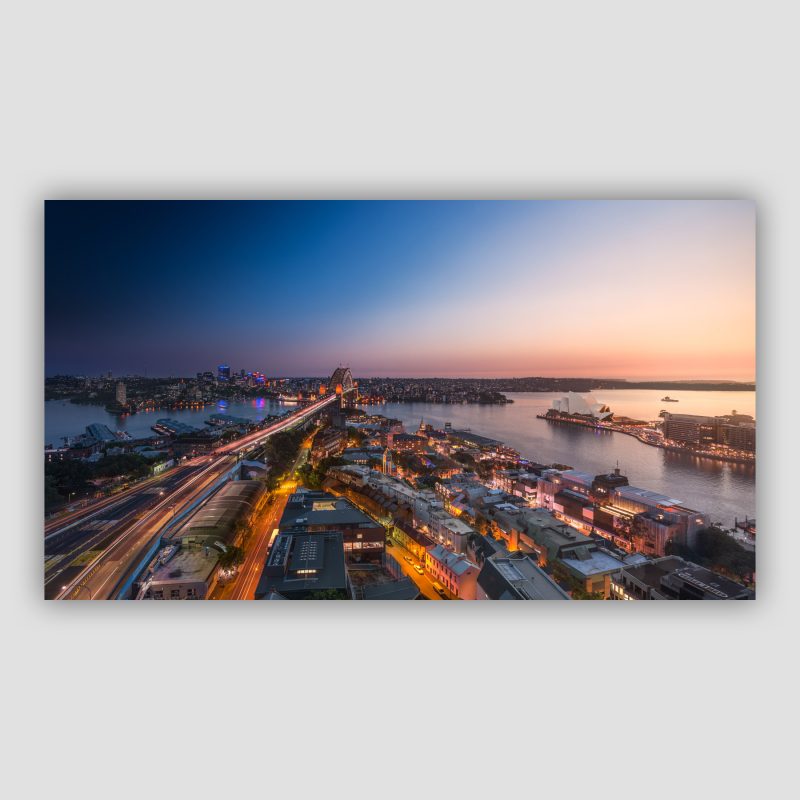 Kunstværket "From Dusk to Dawn" er Fine Art Photography af Surland & Vesterager, der viser lyset skifte henover Sydney med Sydney Harbour Bridge og Operahuset i udsigten. Sælges i Limited Edition.