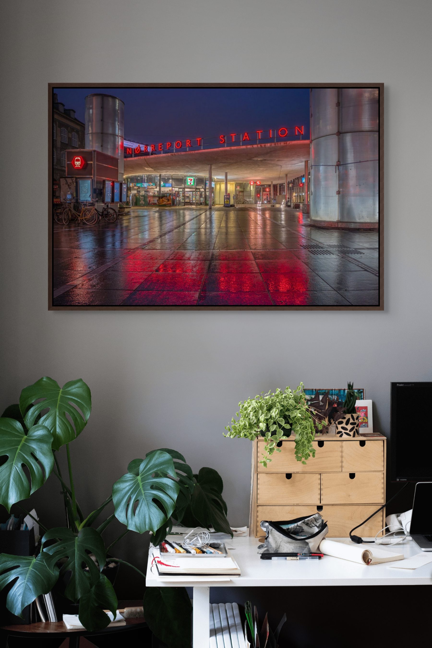 Mockup af kunstværket "Nørreport Station" af Surland & Vesterager. Billedet hænger på en mellemgrå væg i et arbejdsværelse.