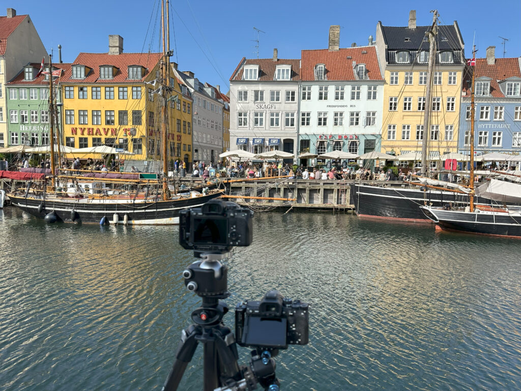 To af vores kameraer, der er stillet op til at fotografere "Et Døgn i Nyhavn", så vi bagefter kan lave et fotokunstværk med lys fra hele døgnet. Billedet er taget henover vandet i Nyhavn midt på eftermiddagen på en dejlig sommerdag, hvor Nyhavn er helt proppet med mennesker. Man kan bl.a. se Heering, Nyhavn 17, Skagen, Cap Horn og Hyttefadet samt nogle af bådene i museumshavnen.