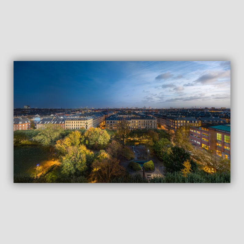 Vi har været så heldige, at få lov til at låne et brag af en udsigt på Frederiksberg på en smuk efterårsaften. Der er udsigt ud over Axel Møllers Have, med Frederiksberg svømmehal i højre side. På horisonten kan man se Københavns Skyline, med Rådhustårnet, Riget, Vor Frue Kirke, Rundetaarn, Bella Sky osv. Billedet er sammensat af billeder taget fra om eftermiddagen til det var blevet helt mørkt. I alt tog vi 664 billeder, hvoraf en delmængde er brugt til det færdige billede.
